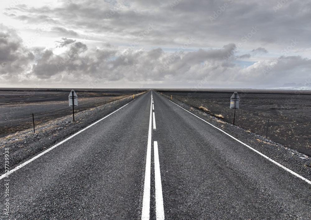 Straight asphalt road running through volcanic desert in Iceland