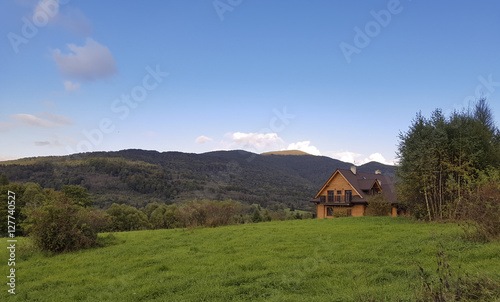 Traditional wooden mountain house on green field in Bieszczady, Poland