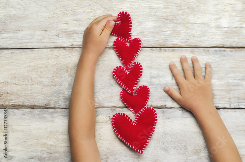 Kid's hands put toy hearts