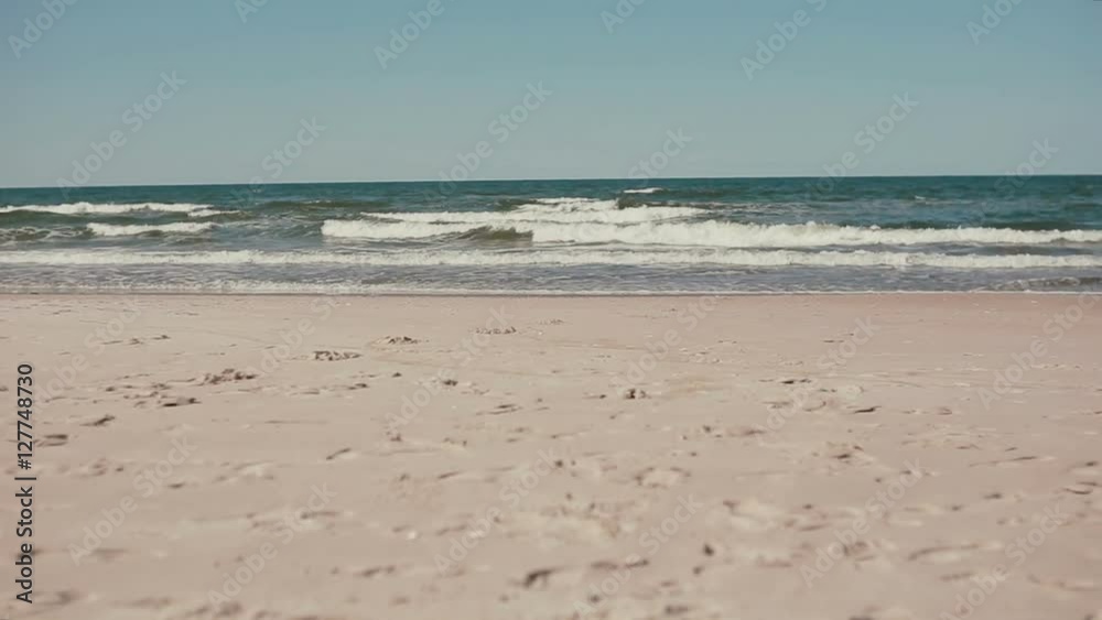 A distant view of a tall sporty man jumping into the water of sea waves on a windy day. A distant view of a tall sporty man jumping into the water of sea waves on a windy day.