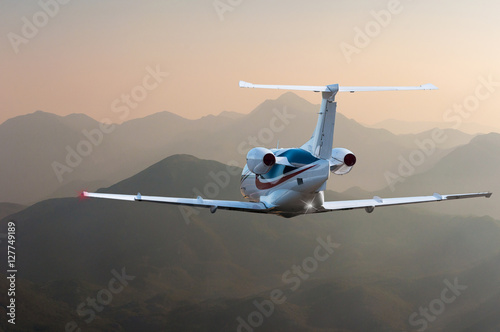 Tela Airplane flying above silhouette of high mountains at sunset