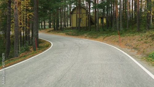 view from the car driving on twisting road through the forest in Finland