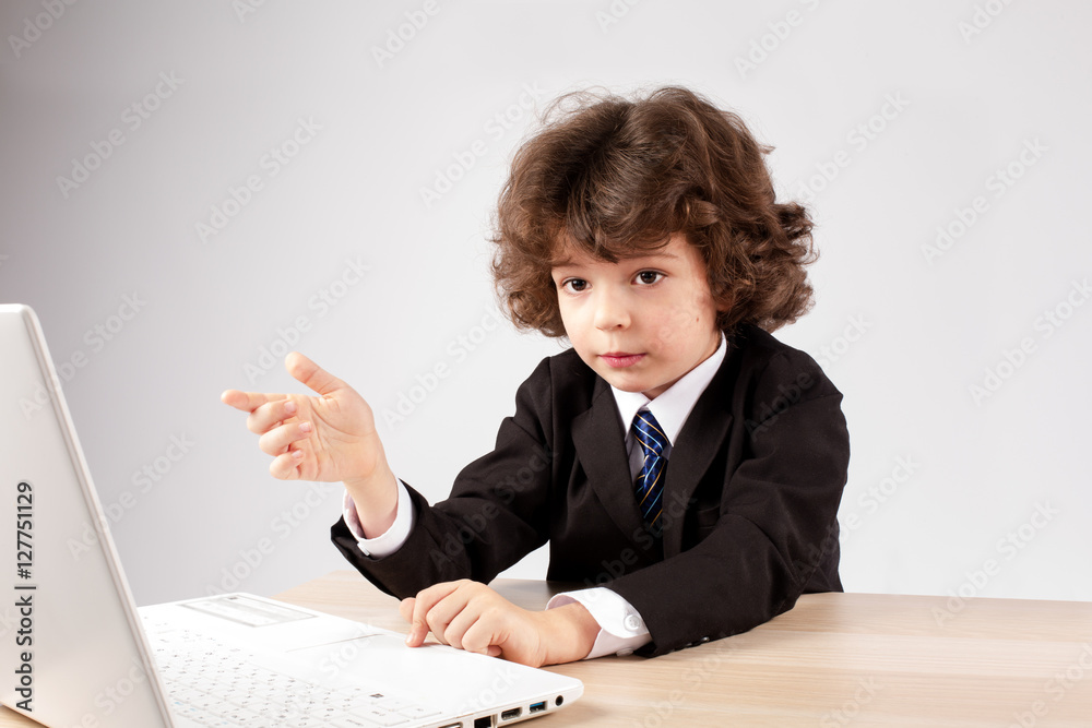Smart small businessman with a laptop says into the camera. Gray background. Smart small businessman with a laptop says into the camera. Gray background.