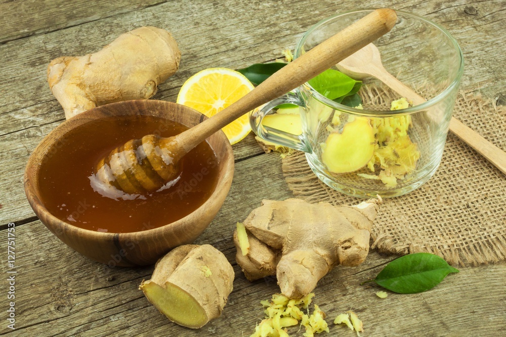 Fototapeta premium Preparing ginger tea against influenza. Traditional treatment for colds. Ginger, lemon and honey bowl on wooden table. Rustic wooden background. Home Pharmacy.