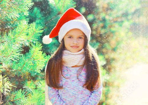 Christmas portrait child little girl in santa red hat near a tre