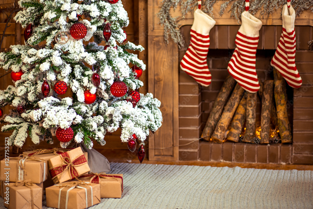 Fototapeta premium Beautiful holiday decorated home room with Christmas tree, gifts under it and red Christmas socks.
