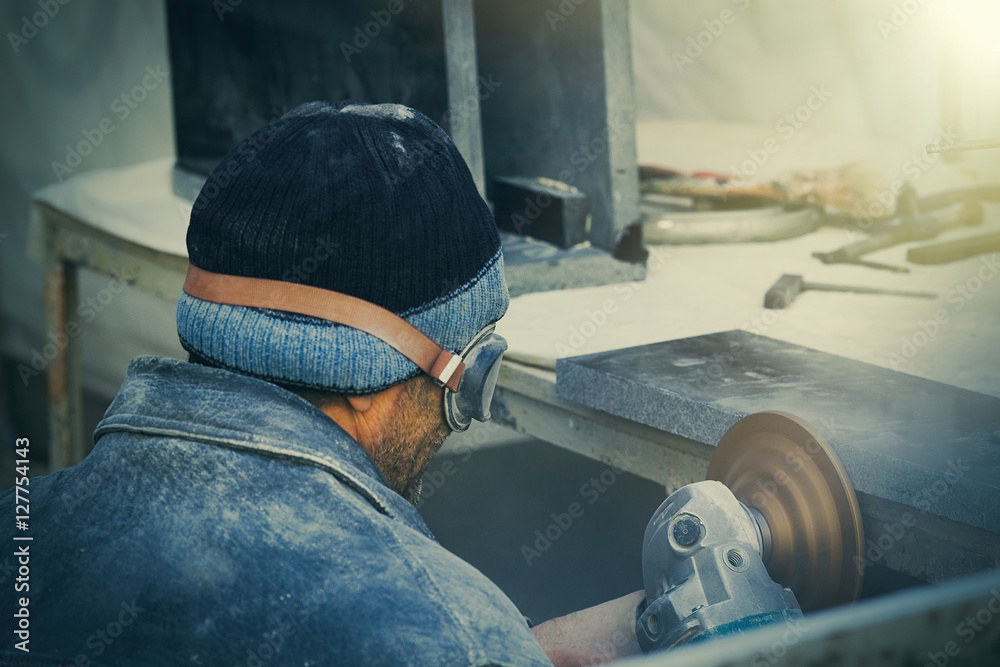 Obraz premium A worker sculptor cuts the granite.