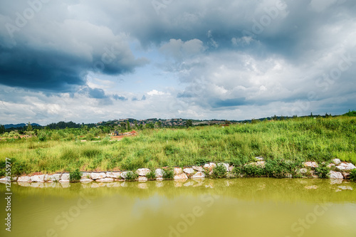 Beautiful view of a small lake edged by green trees at autumn cl