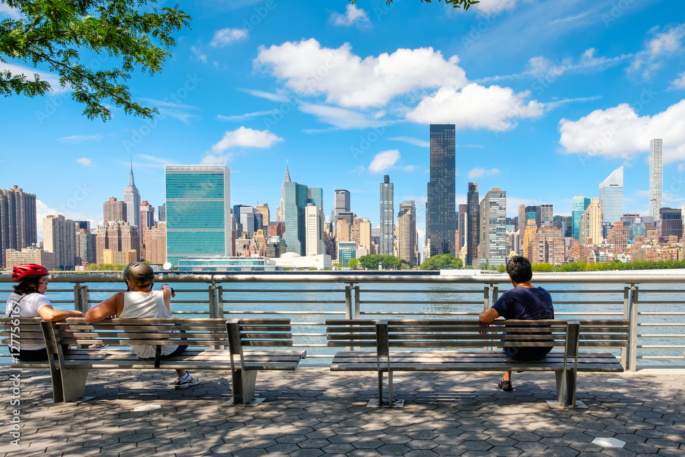 Naklejka premium NewYorkers at a park in Queens with a view of the midtown Manhattan skyline