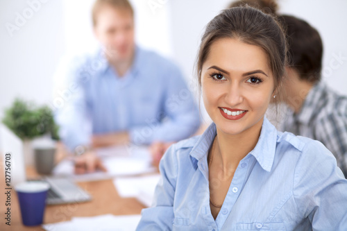 Beautiful business woman on the background of business people during meeting. Casual clothing style.