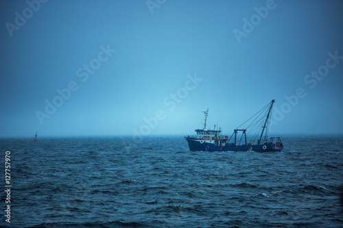 Trawler fishing boat sailing in open waters on a cold and foggy