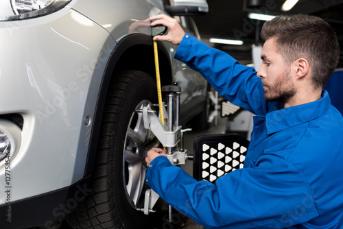 Professional mechanic adjusting automobile wheel alignment
