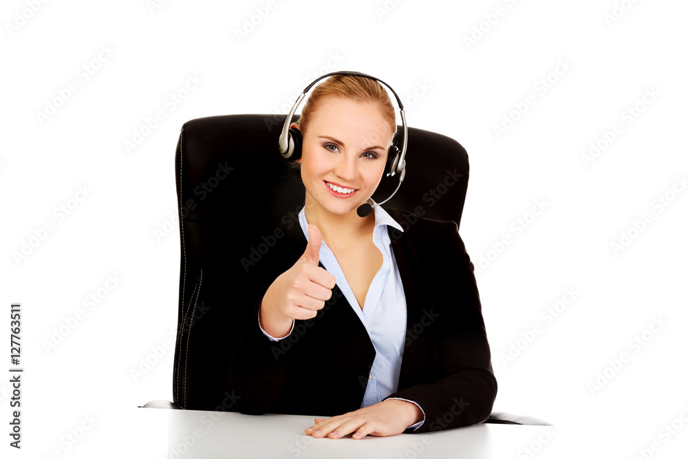 Smiling phone operator in headphones sitting behind the desk Smiling phone operator in headphones sitting behind the desk