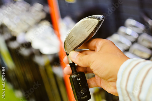 Closeup on person holding golf club in hand, shop background