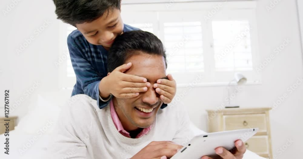 Father and son using digital tablet on the bed Father and son using digital tablet on the bed