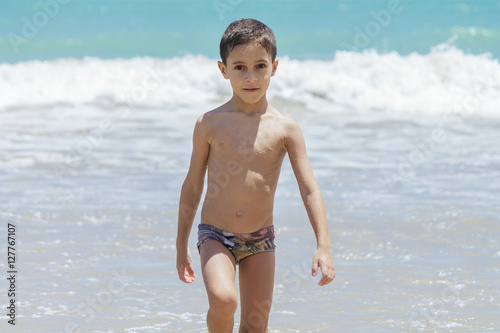 Six year old boy having fun on tropical beach in sunny day