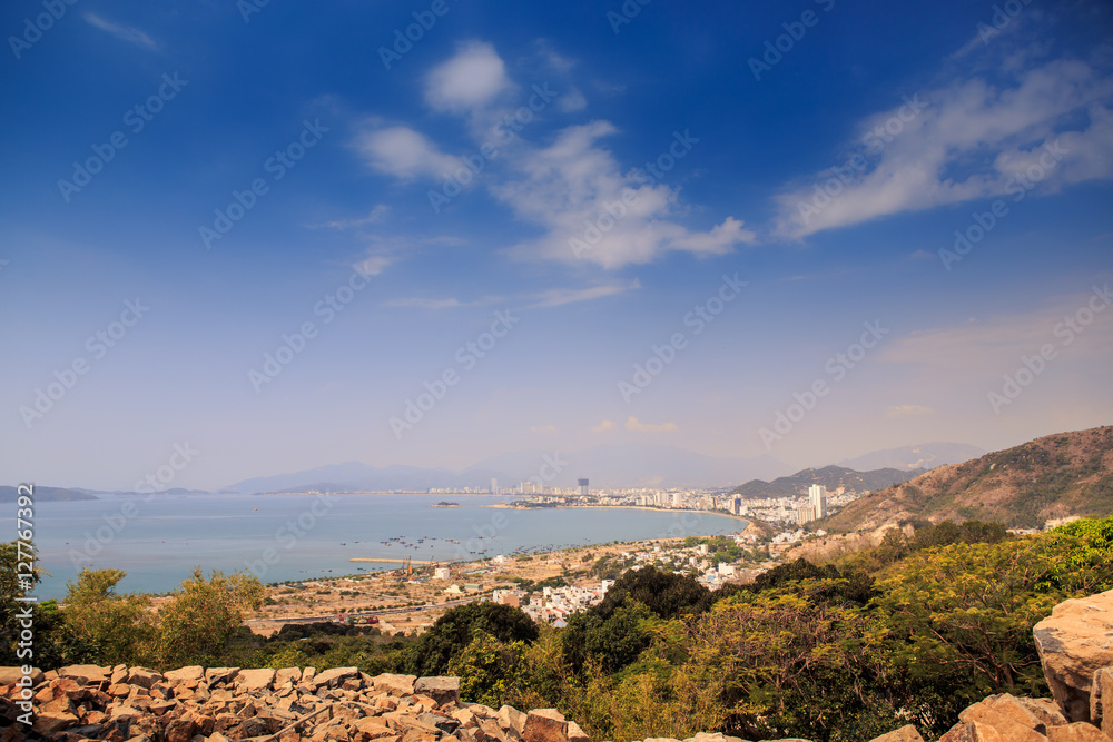 panorama of rocky green hills against blue sea and bright sky with clouds