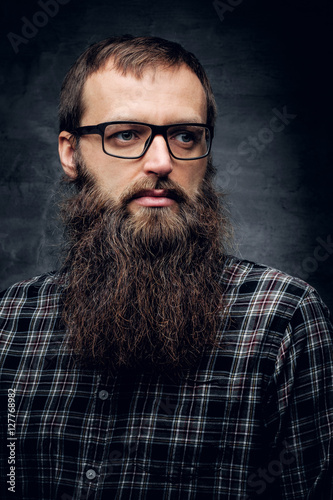 A bearded male in sunglasses dressed in a plaid shirt.