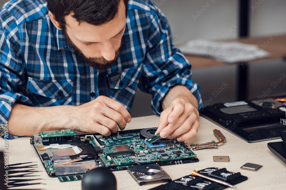 © golubovy - Repairman disassembling laptop motherboard. Engineer fixing broken computer at work. Electronic repair shop, technology renovation, business, occupation concept
