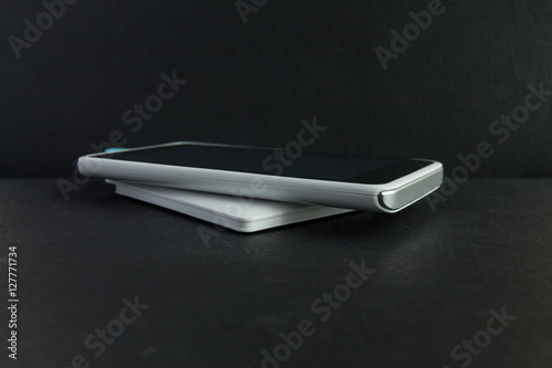 Smartphone charging with power bank on black background