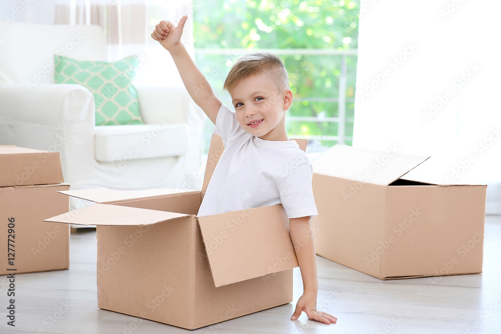 Little cute boy playing with cardboard boxes at home Little cute boy playing with cardboard boxes at home