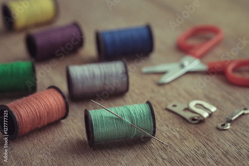 Thread with needle and scissors on wooden table, Vintage tone