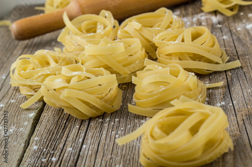 Nests of raw fettuccine pasta on the wood background