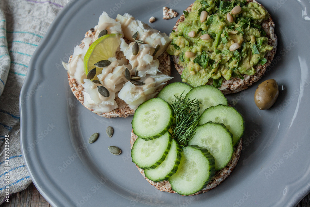 Round buckwheat or rye bread with guacamole, cucumber and fish with tahini. Love for a healthy raw food concept Round buckwheat or rye bread with guacamole, cucumber and fish with tahini. Love for a healthy raw food concept