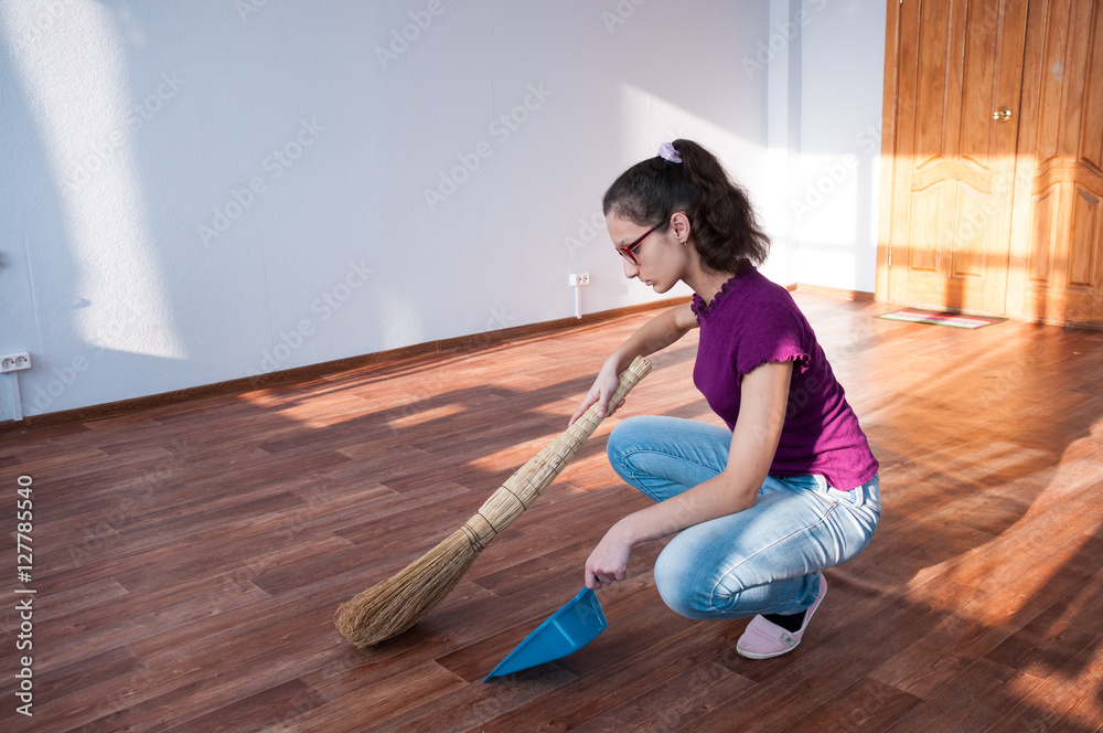 Girl with a broom making cleaning an empty apartment Girl with a broom making cleaning an empty apartment