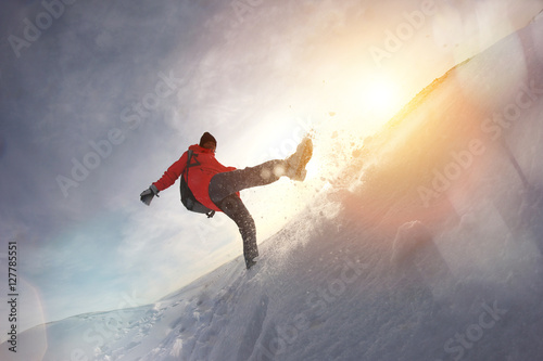 Girl in winter clothes and a backpack walking on snow hills. Snow flies from under his feet. Lens flare effect
