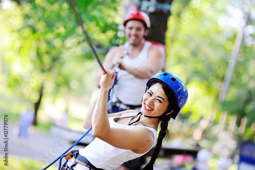 boy and girl climbing on rope road in a special outfit and helmet. The instructor of rock climbing and overcoming obstacles