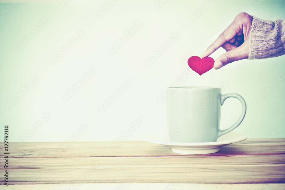 hand holding red heart shape put into a Coffee cup mug hand holding red heart shape put into a Coffee cup mug