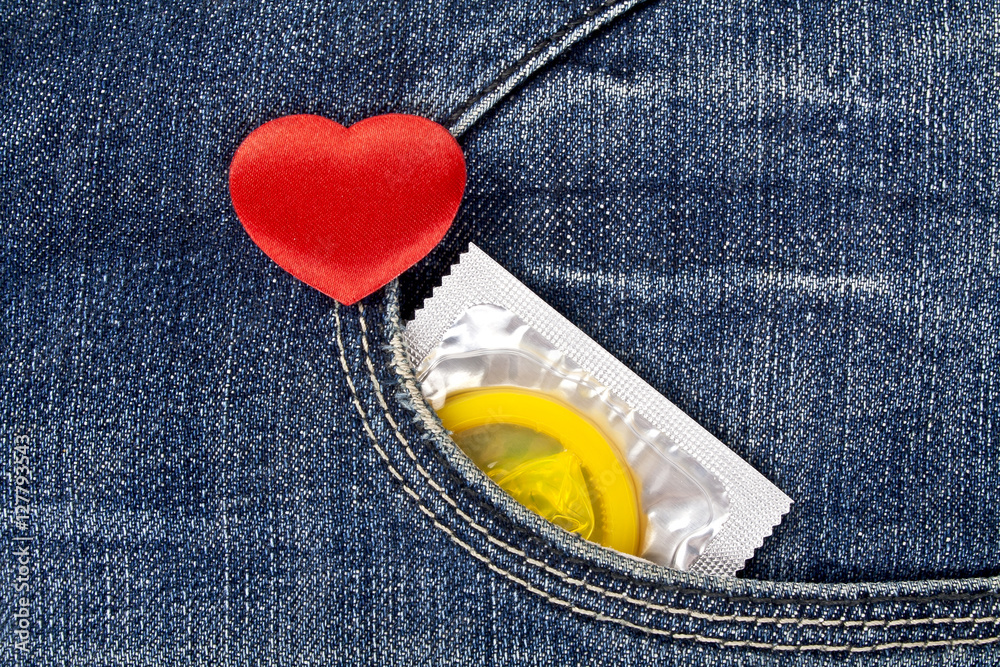 Rea heart and yellow condom in blue jeans pocket Stock Photo | Adobe Stock