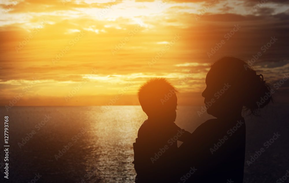 Silhouette of mother and baby on sunset