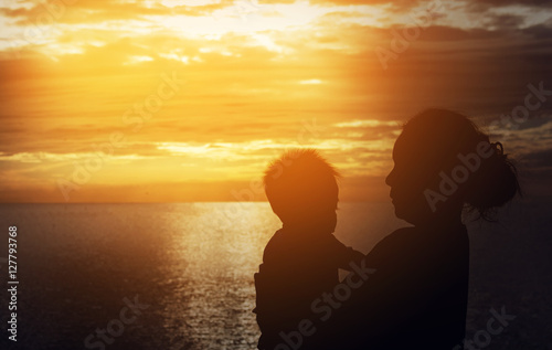 Silhouette of mother and baby on sunset