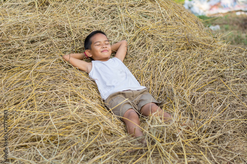 Happy Children wearing a white shirt sleeping on straw.