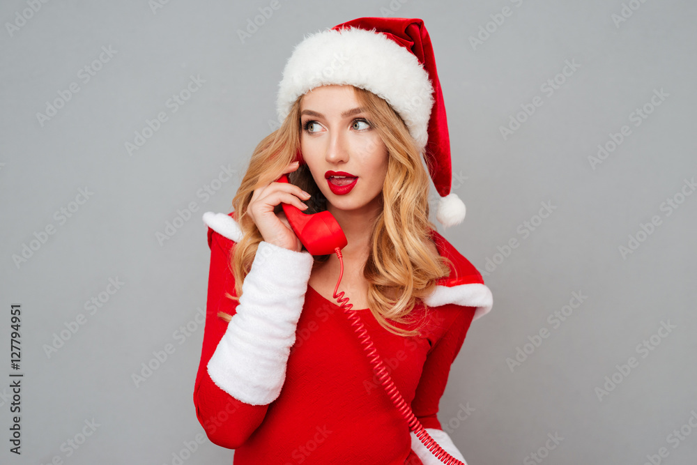Attractive blonde young woman in santa costume talking on telephone Attractive blonde young woman in santa costume talking on telephone