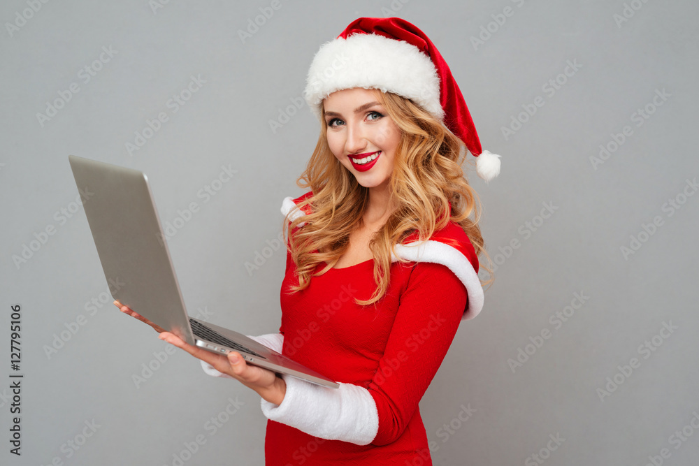 Woman in red santa claus outfit holding laptop
