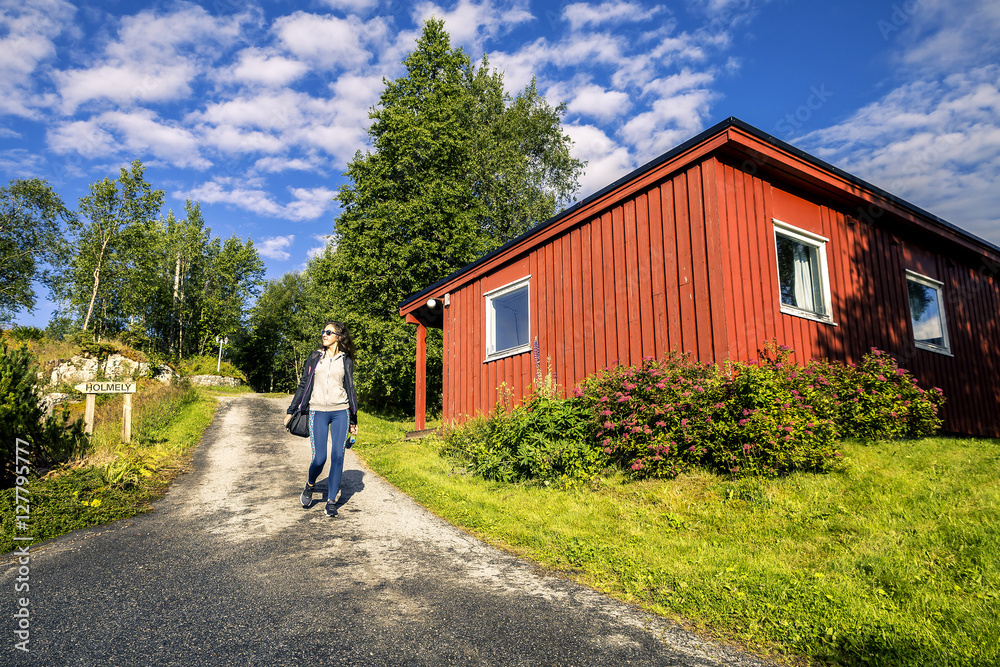 Young woman is walking near by red house, Norway