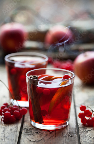 Winter warm drink. Glasses with hot punch or sangria for Christmas. Ingredients - orange and apple slices, berries, cinnamon and spices. Mulled wine
