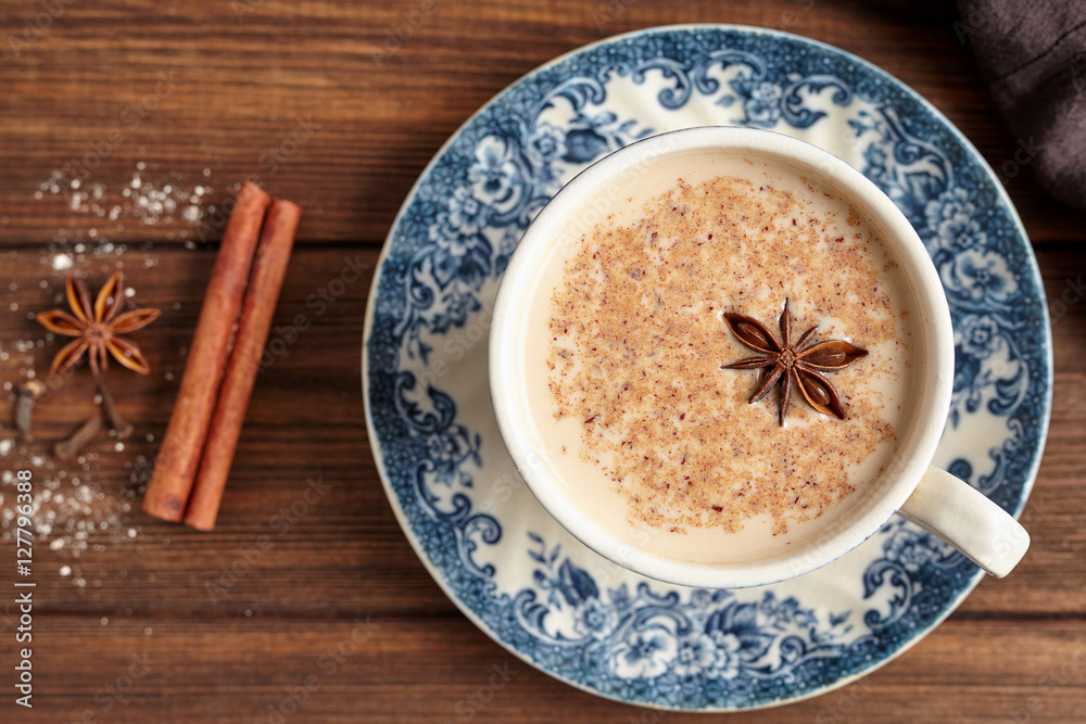 Masala tea chai latte traditional hot Indian sweet milk with spices, cinnamon stick, herbs blend organic infusion healthy beverage in porcelain cup on wooden table background Masala tea chai latte traditional hot Indian sweet milk with spices, cinnamon stick, herbs blend organic infusion healthy beverage in porcelain cup on wooden table background