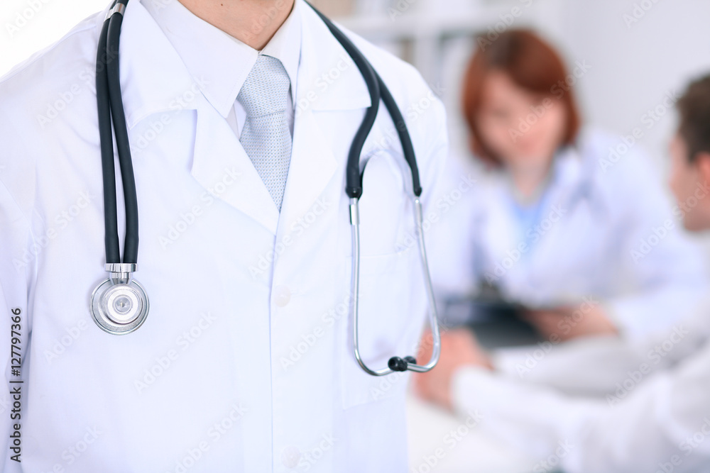 Close-up of a male doctor in a background of doctor and patient Close-up of a male doctor in a background of doctor and patient