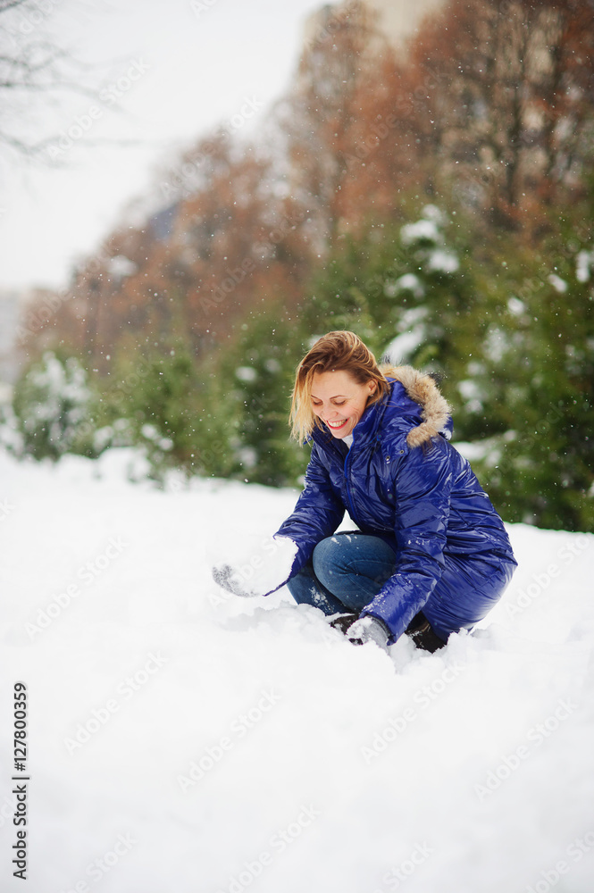 Young woman in the winter park begins to build a snowman. I