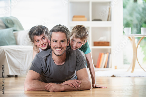 At home, Dad and kids lying on wooden floor in the living-room