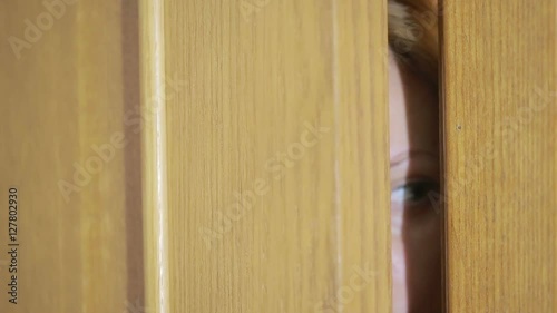 girl spies through a door crack. Eye looking through a slit photo