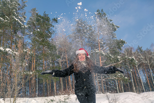 Young beautiful smiling woman throwing snow in the air in winter holidays