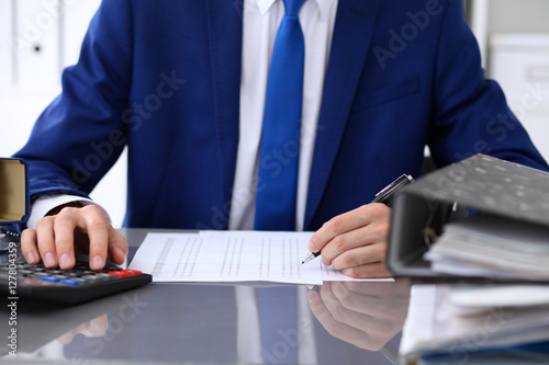 Close up view of bookkeeper or financial inspector hands making report, calculating or checking balance. Internal Revenue Service inspector checking financial document.