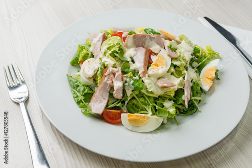 Nutritious vegetable salad with boiled egg slices and salmon