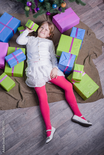 Girl lying on the floor among Christmas gifts