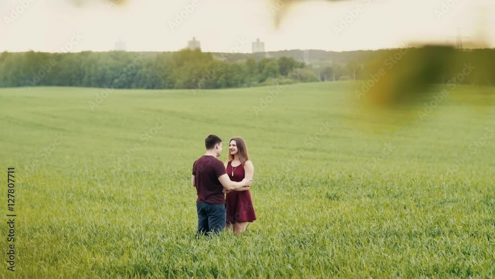 Loving couple hug, standing in a field. They smile happily, look at each other, hold hands. Slow mo Loving couple hug, standing in a field. They smile happily, look at each other, hold hands. Slow mo
